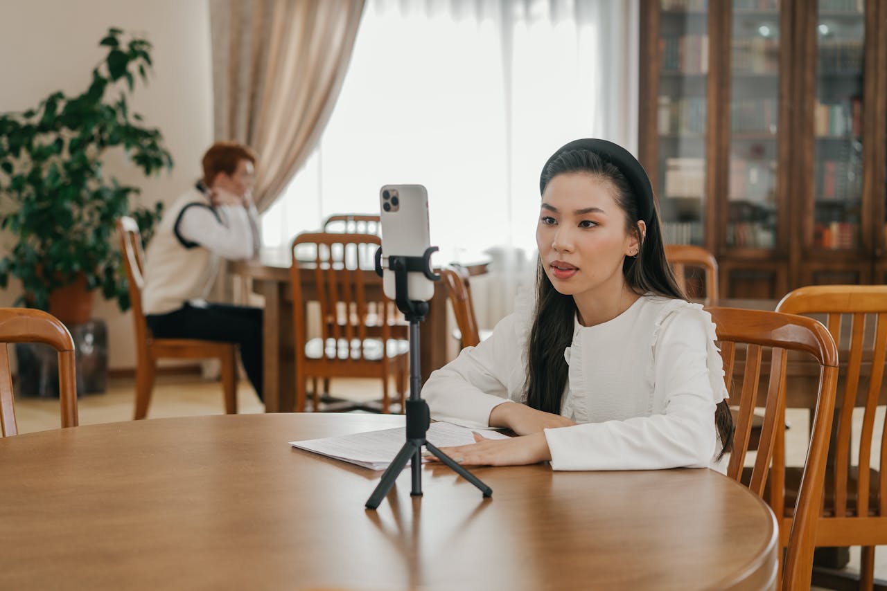 story-01 Young woman creating vlog content using a smartphone in a cozy indoor setting with wooden furniture.